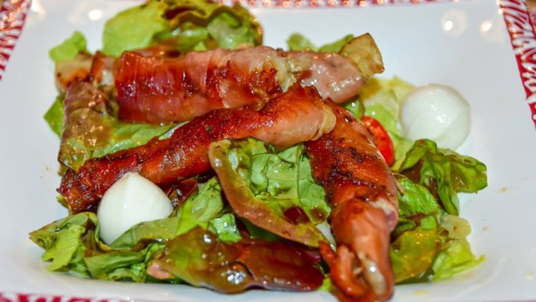 Dish with carp wrapped in ham on a leaf salad.