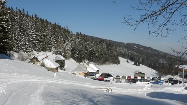 Snow-covered landscape with huts and parked cars near Steyersberger Schwaig.