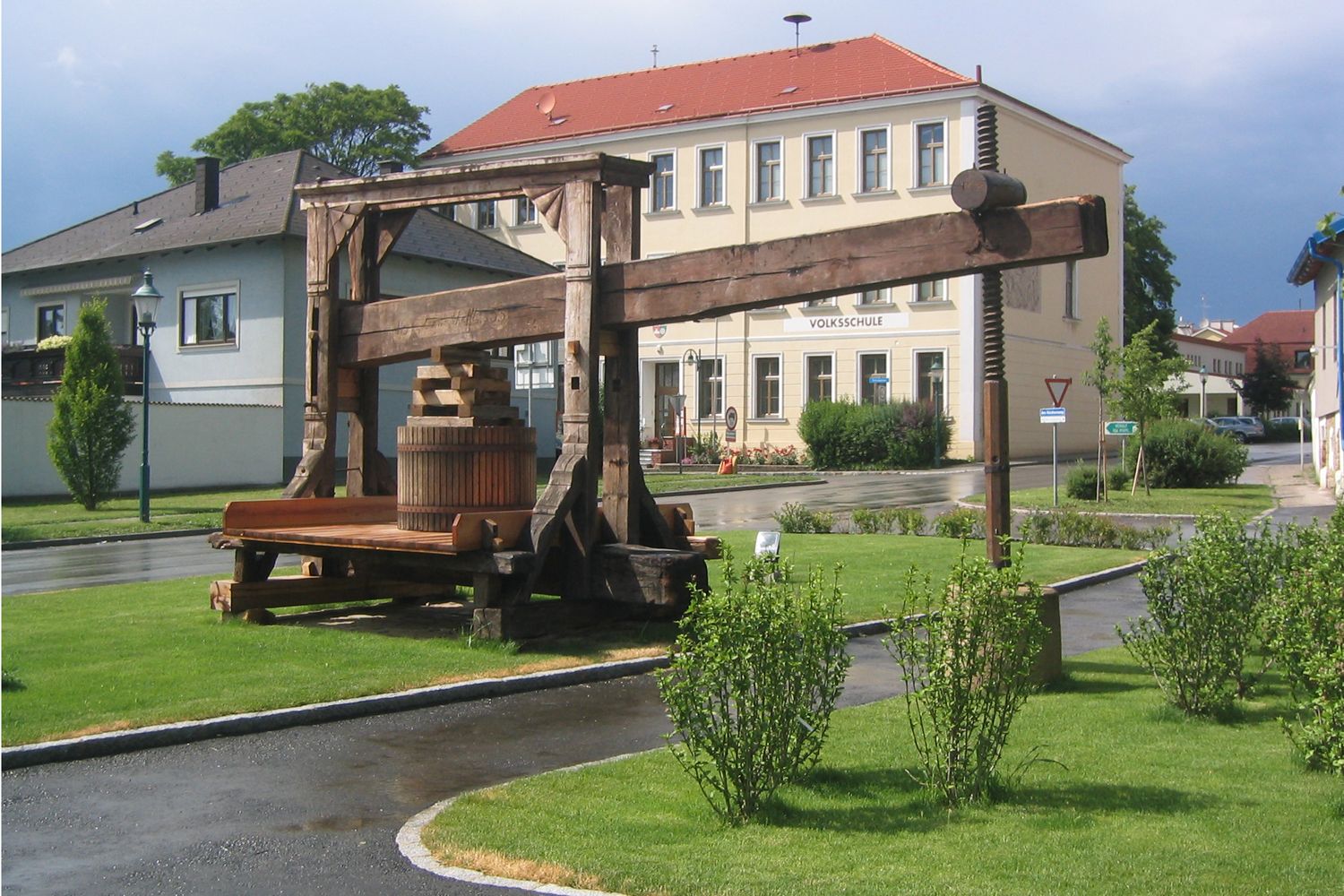 Historic tree press in front of a school building in a green setting.