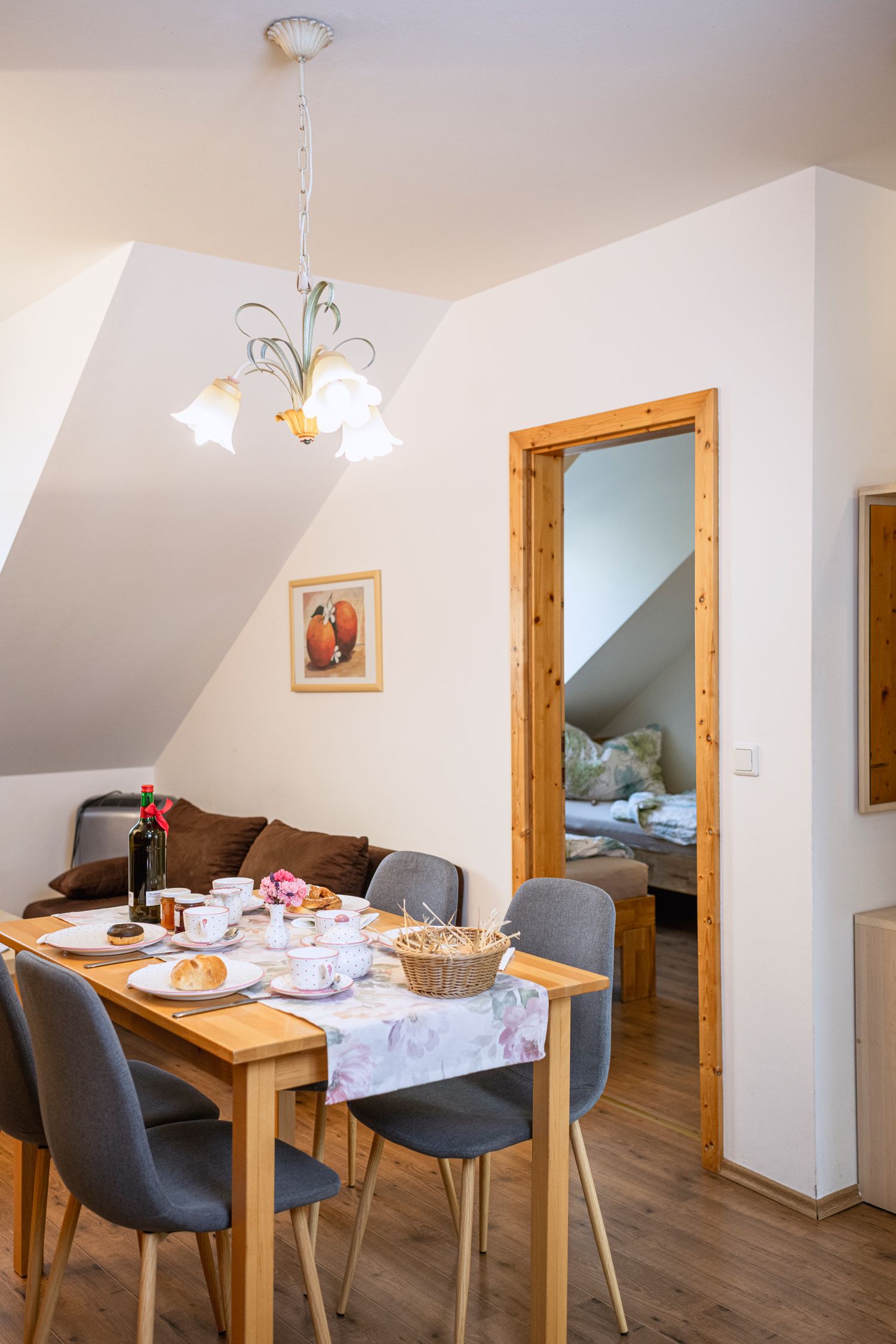 Dining area in a vacation apartment with set table and view into the bedroom.