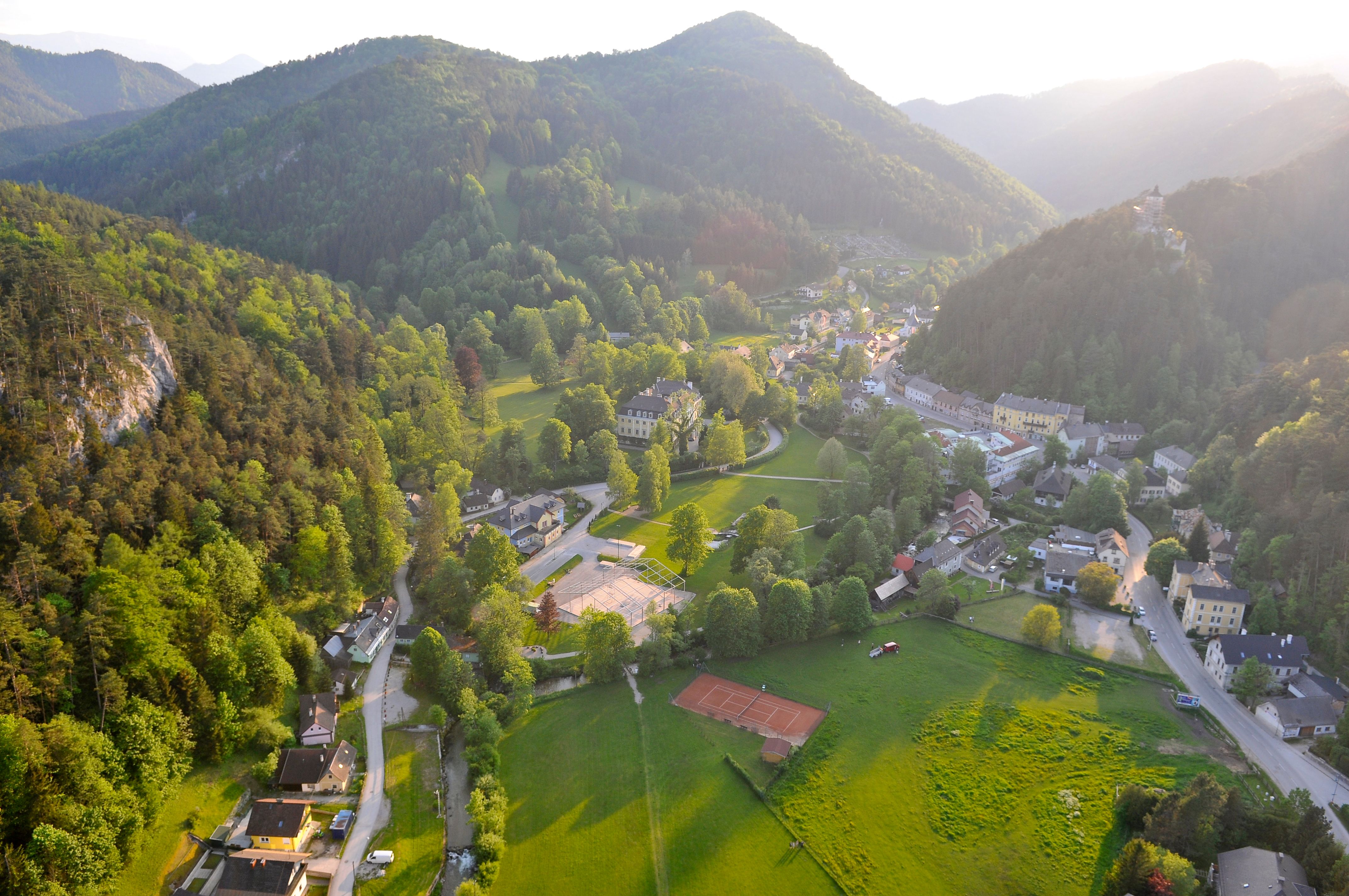 Aerial view of Gutenstein, surrounded by green hills and forests, with buildings and roads in the valley.