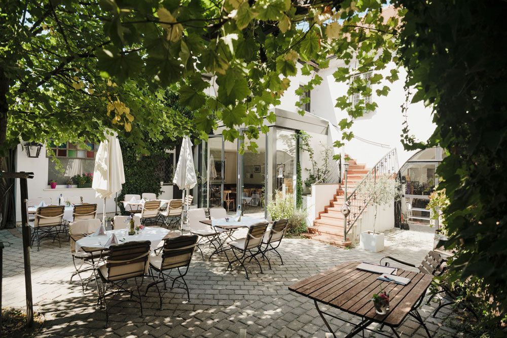 Cozy courtyard with tables, chairs and green arbor.