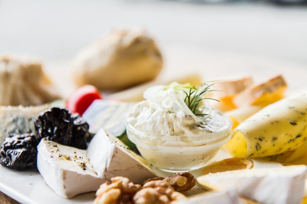 Close-up of a cheese platter with different types of cheese, nuts, dried fruit and a dip.