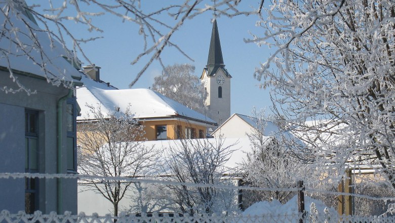 Snowy village view with church and trees in winter.