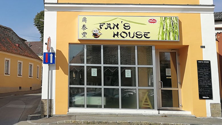 Exterior view of a restaurant called Fan's House with a yellow façade and large windows.