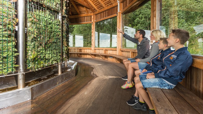 Family sitting in a wooden pavilion in front of a salt works.