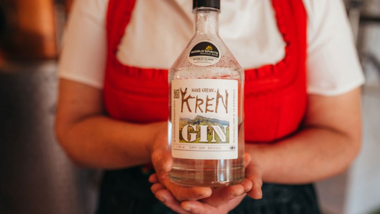 Person holding a bottle of Krenn gin with a label.