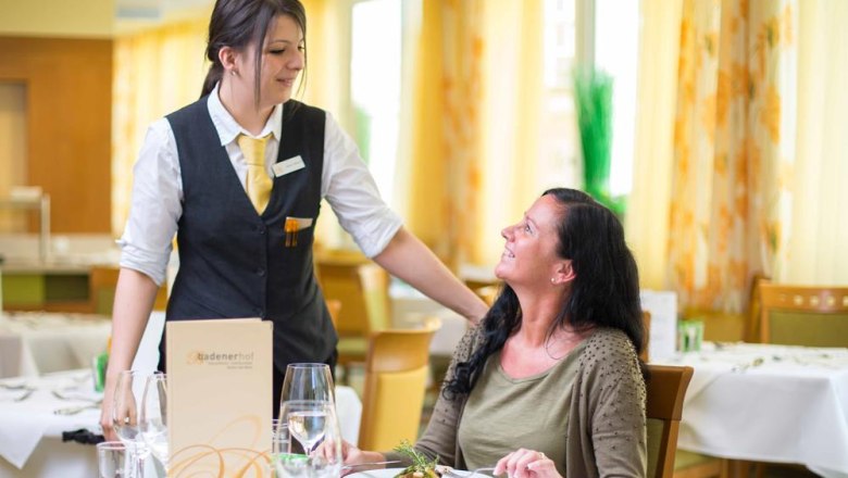 A waitress serves a woman in a restaurant.