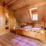 Bedroom with wood paneling, large double bed, wooden wardrobe, carpets and a window.