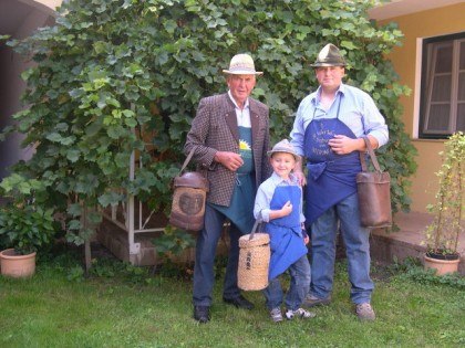 Three generations of men in traditional clothing with baskets in the garden.