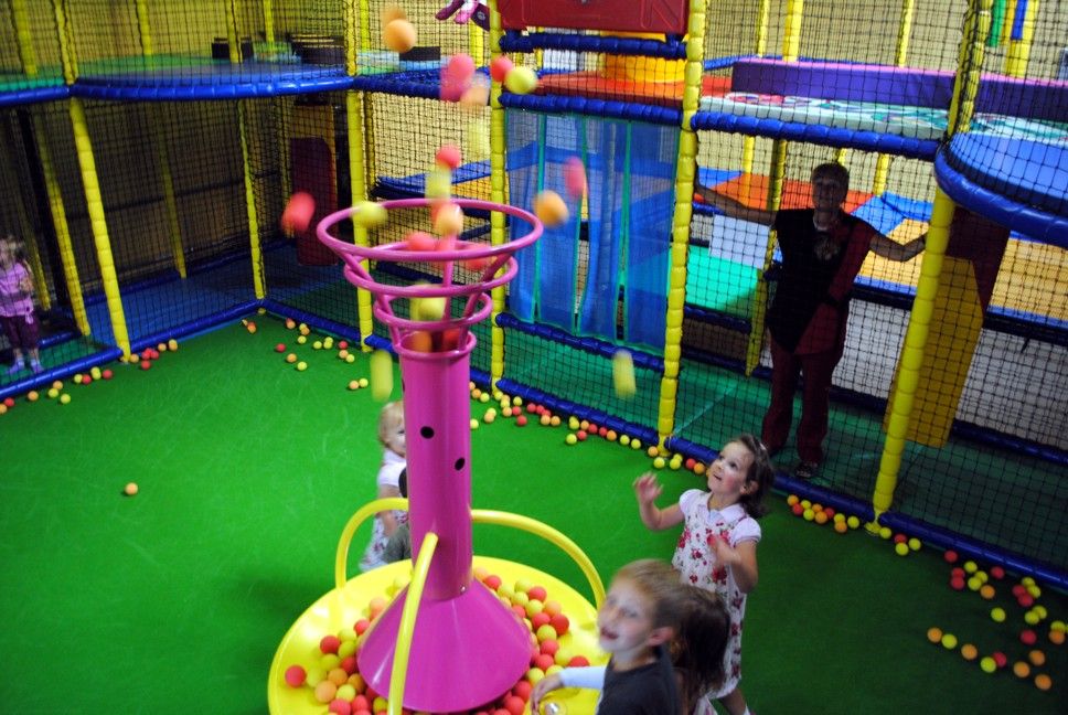 Children playing in an indoor playground with a ball fountain.