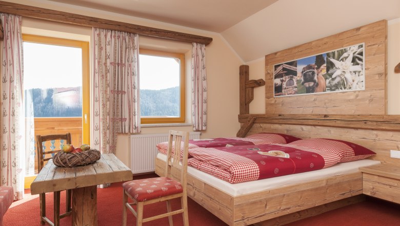 Cozy room in alpine style with wooden furniture, red carpet and mountain view.