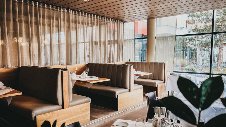 Interior view of an elegant restaurant with wooden furniture and large windows.