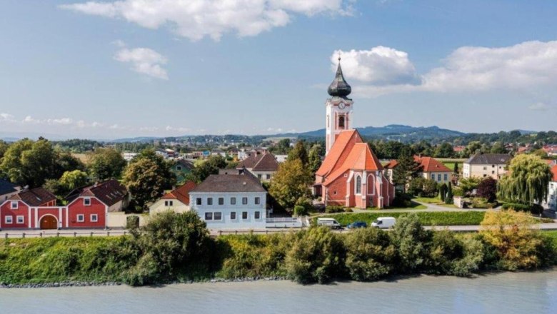 Landscape view of Persenbeug-Gottsdorf with church and river in the foreground.