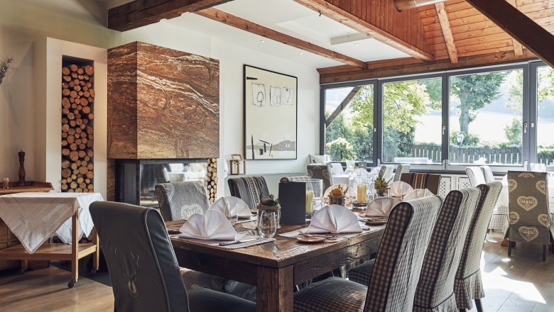 Elegant restaurant with wooden beams, fireplace and covered tables.