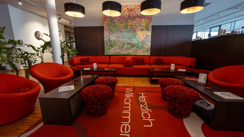 Modern hotel lobby with red furniture and artwork on the wall.