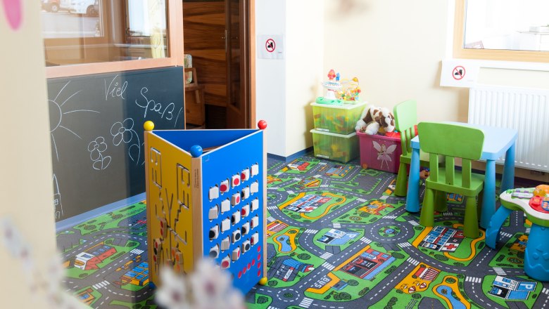 A colorful children's playroom with carpet, toys and small furniture.