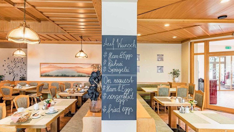 Breakfast room with wooden furniture and a board with breakfast options.