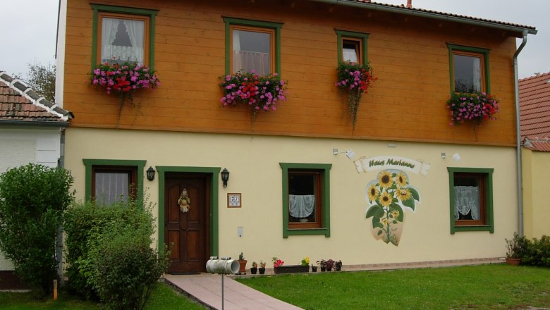 TD, House Marianne, Pischelsdorf, house view, © Reiter Two-storey house with wooden cladding and flower boxes, labeled 'Haus Marianne'.