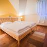 Cozy bedroom with double bed, wooden floor, yellow wall and large mirror.