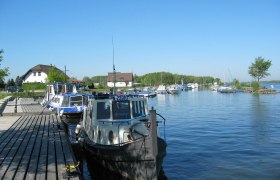 Boats on a jetty in a quiet harbor with a blue sky.