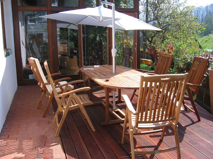 Wooden terrace with table, chairs and parasol.