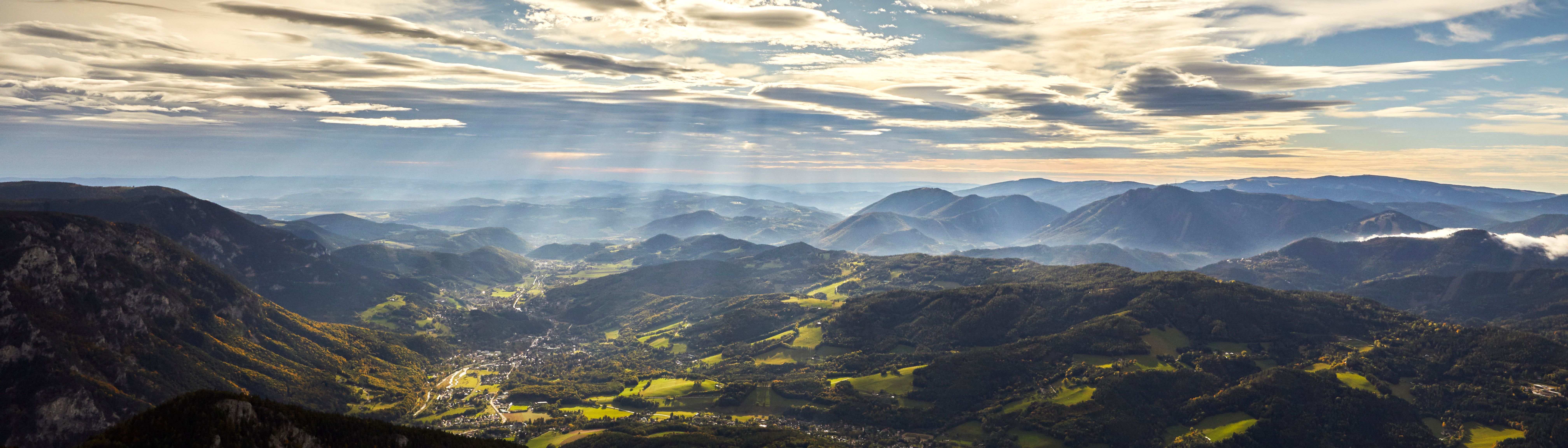 Panoramic view of the Rax Alps with sunbeams and clouds in the sky.