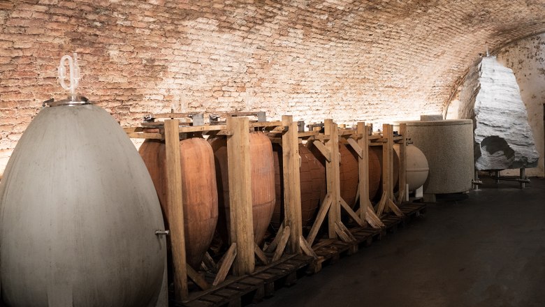 Wine cellar with large fermentation vats and brick wall.