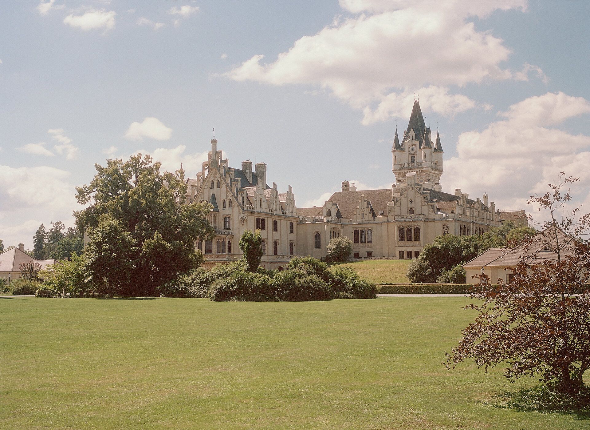 Grafenegg Castle with extensive lawn and trees in the foreground.
