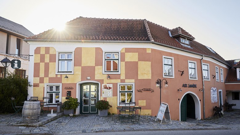 Historic building with yellow and red façade, sunshine in the background.