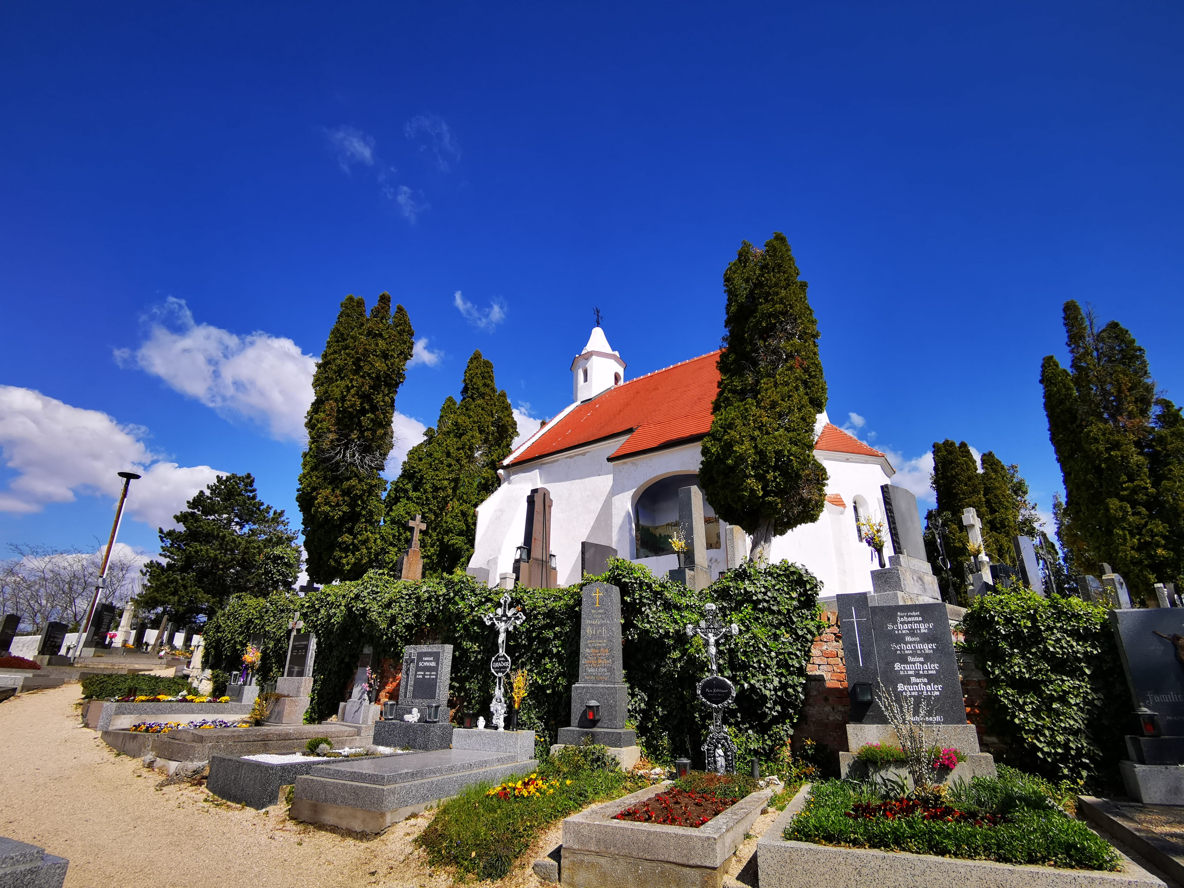 Kunigungenkirche church in Mailberg with cemetery and flowering graves in the foreground.