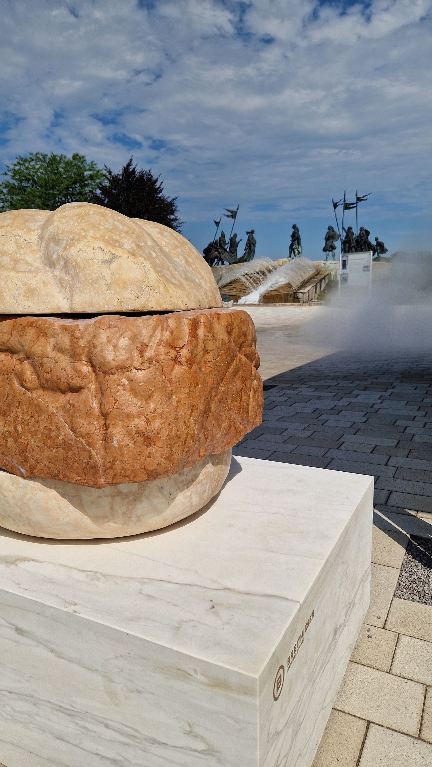 Leberkässemmel statue in front of Hans Wurst snack stand in the background Nibelungen fountain