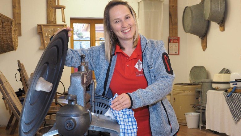 A woman in a museum shows an old washing machine.
