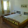 Bedroom with double bed, yellow bed linen, wooden furniture and floral curtains.