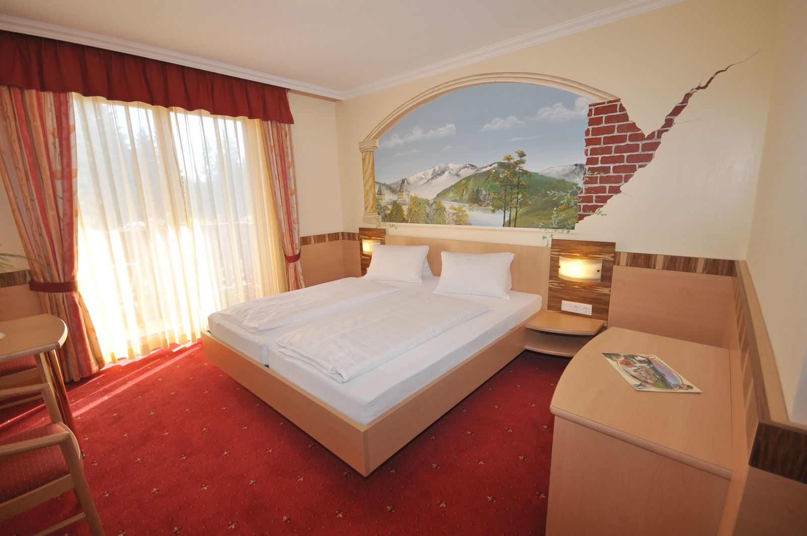 Double room with double bed, wall painting and red carpet.