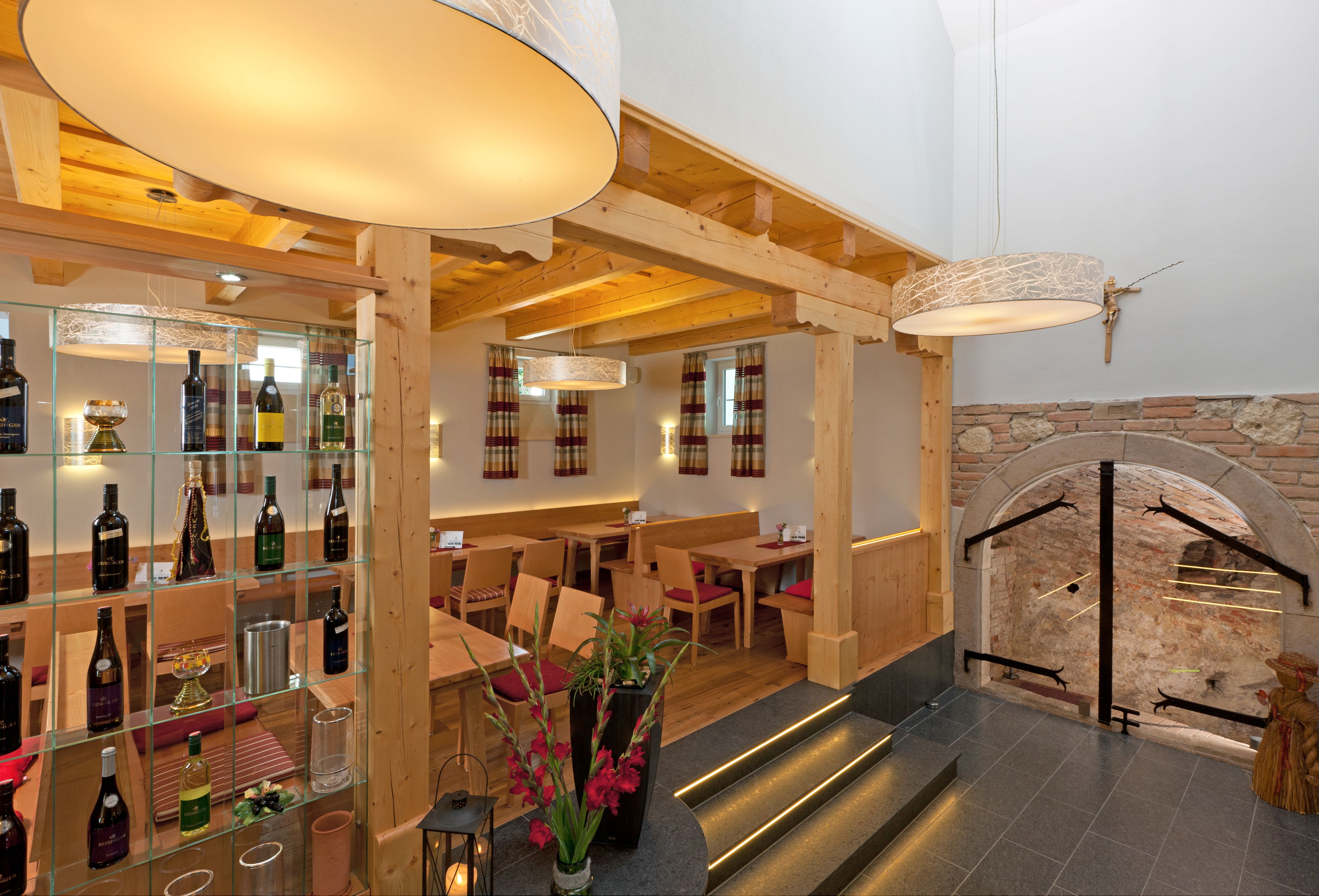 Interior view of a wine tavern with wooden furniture, wine rack and decorative lamps.
