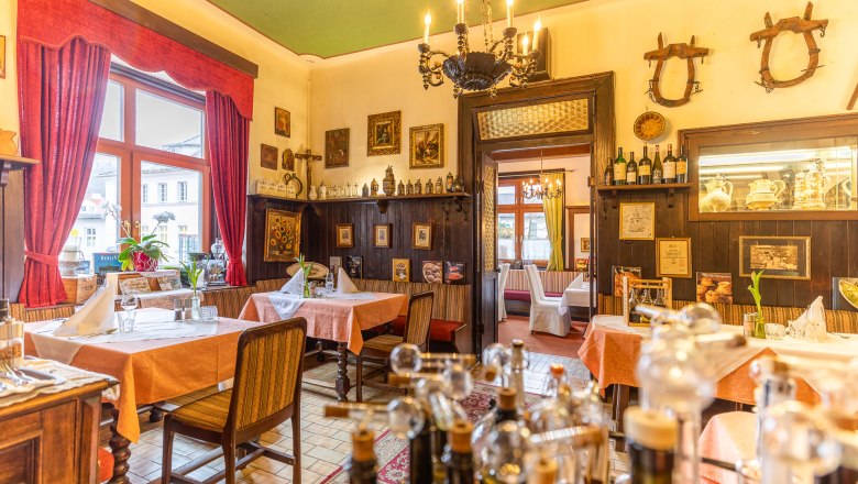 Cozy restaurant with wooden furniture, red curtains and decorative pictures on the walls.