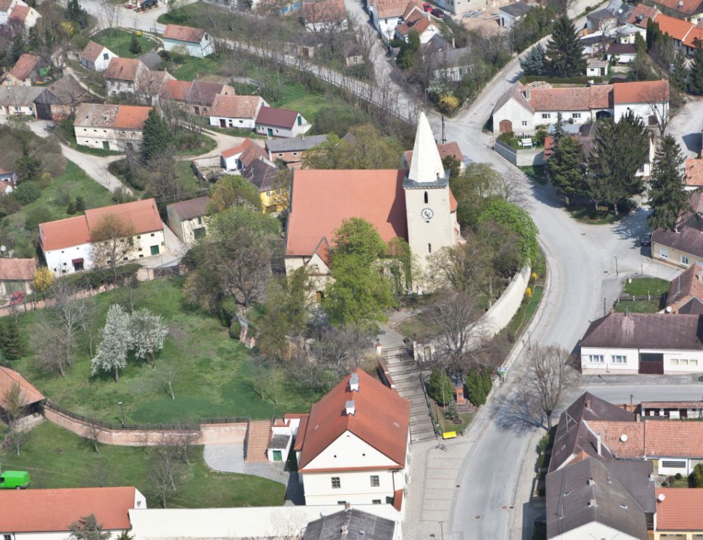 Aerial view of a church in a village with surrounding houses and streets.