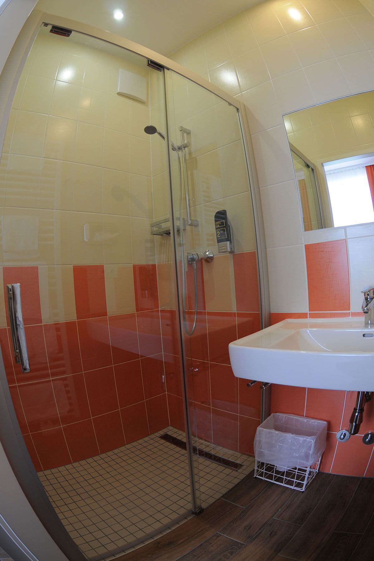 Bathroom with shower, washbasin and orange and white tiles.