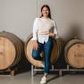 A woman leans smiling against a wine barrel at the Haimel winery.