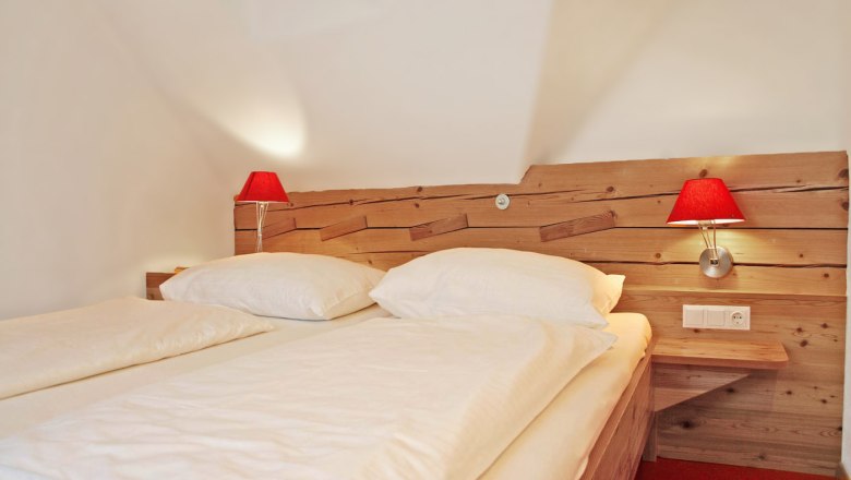 Guest room with wooden bed and red lamps.