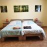 Bedroom with two single beds, bedside tables and forest landscape pictures on the wall.