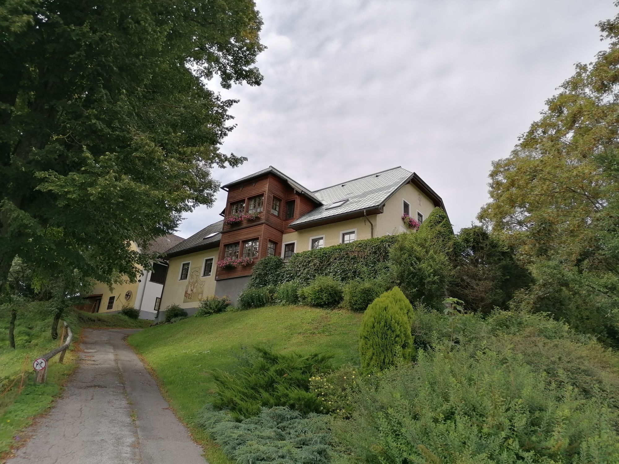 A large house on a hill with trees and a path in the foreground.