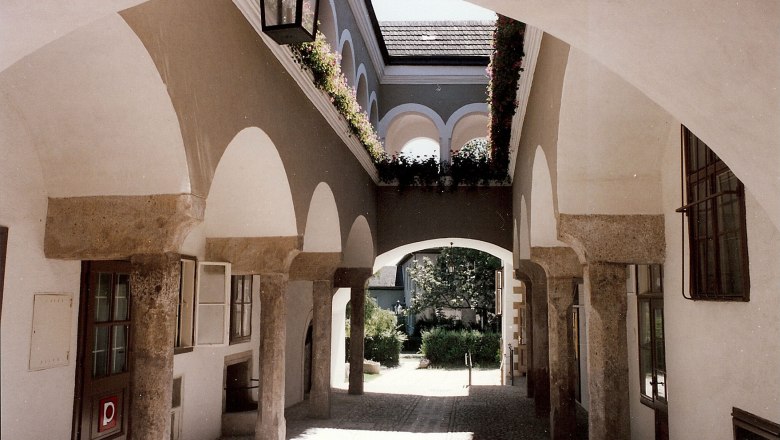 An arcaded courtyard with stone arches and flowers in the Hafnerhaus.