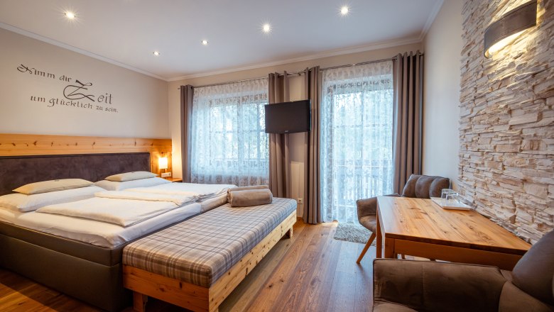 Cozy bedroom with double bed, wooden furniture and stone wall.