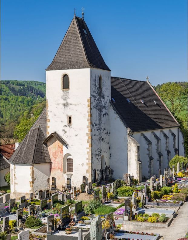 Rustic fortified church in Bromberg with a broad tower and cemetery in the foreground.
