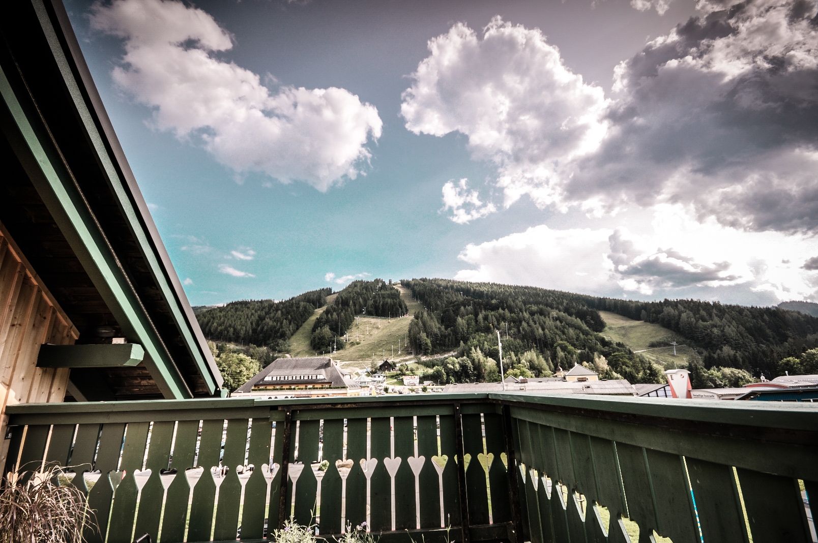 View from a balcony of a green mountain landscape with clouds in the sky.