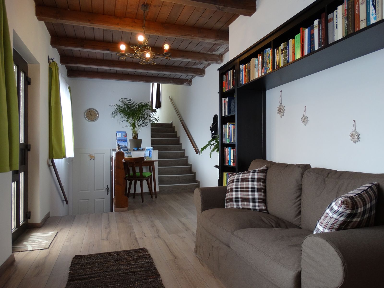 Living room with brown sofa, bookshelf and staircase in the background.