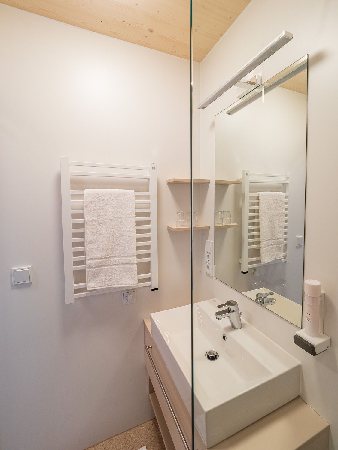 Modern bathroom with washbasin, mirror and towel rail.