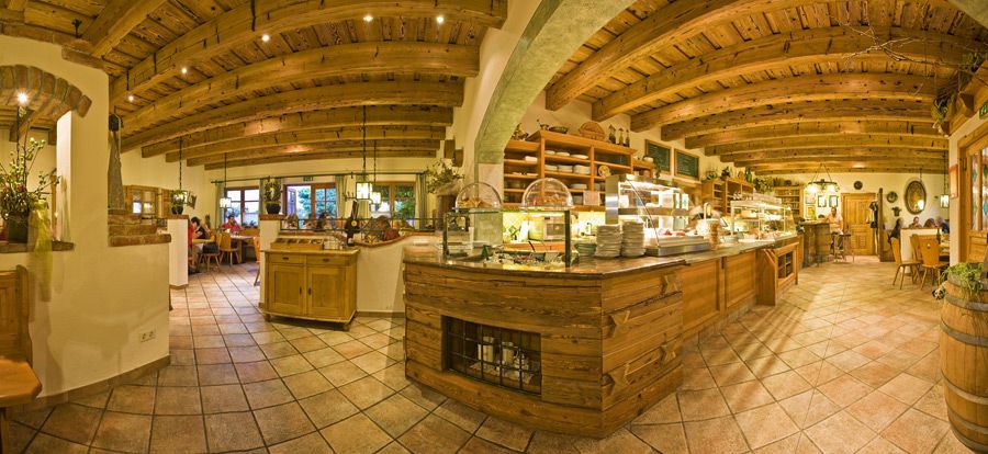 Interior view of a cozy wine tavern with wooden beam ceiling and rustic furnishings.